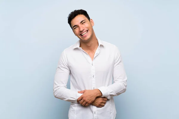 Handsome man over blue wall smiling