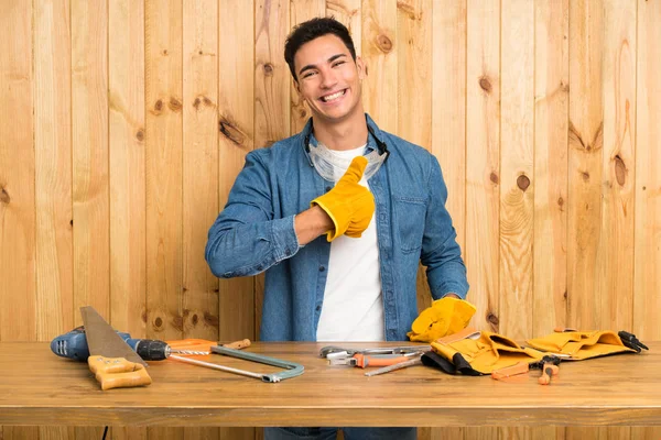 Craftsmen man over wood background giving a thumbs up gesture