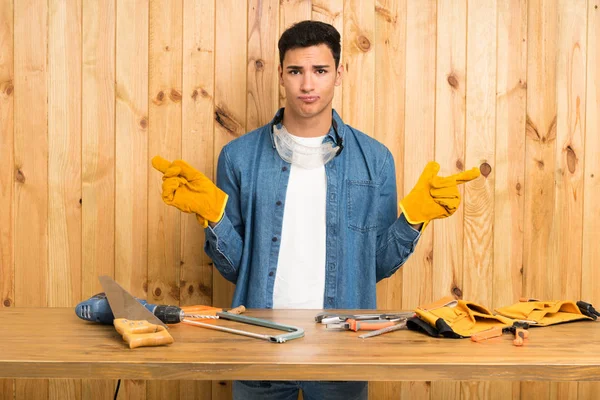 Craftsmen man over wood background pointing to the laterals having doubts