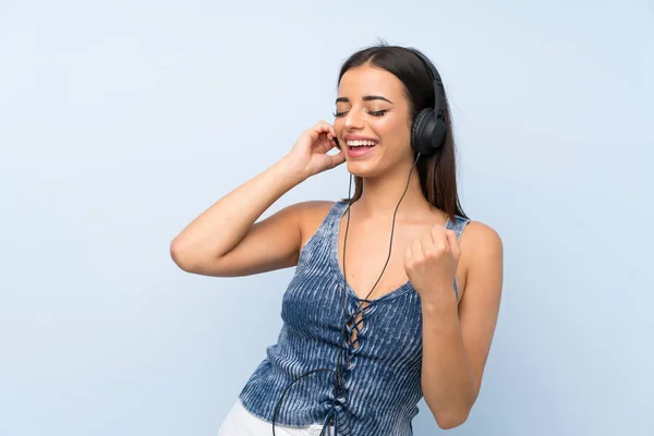 Νεαρή Γυναίκα Πάνω Από Απομονωμένο Μπλε Τοίχο Ακούγοντας Μουσική Ακουστικά — Φωτογραφία Αρχείου