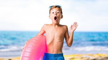 Plajda sürpriz ve şok yüz ifadesi ile yaz tatilinde çocuk