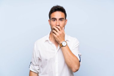 Sağ görünümlü iken izole mavi arka plan üzerinde yakışıklı genç adam şaşırttı ve şok