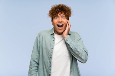 Sürpriz ve şok yüz ifadesi ile izole mavi duvar üzerinde genç Afrikalı Amerikalı adam