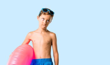 Yaz tatilinde çocuk şüphe ve izole mavi arka plan üzerinde yüz ifadesi karıştırmaya sahip