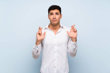 Parmakları geçiş ve en iyi dilek ile mavi duvar üzerinde Yakışıklı adam