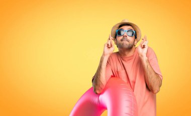 Parmak geçişi ve en iyi dilek ile onun yaz tatili üzerinde şapka ve güneş gözlüğü ile adam. Bir dilek tut. turuncu arka planda