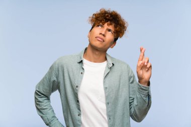 Parmak geçişi ile izole mavi duvar üzerinde genç Afrikalı Amerikalı adam ve en iyi dilek