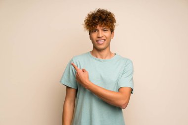 Yeşil gömlekli Afrikalı-Amerikalı adam bir ürün sunmak için yan işaret