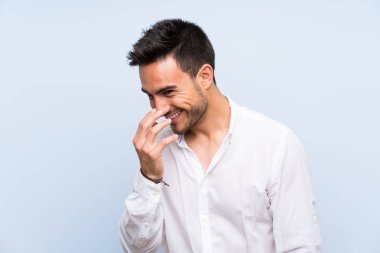 Yakışıklı genç adam üzerinde izole mavi arka plan çok gülümseyen