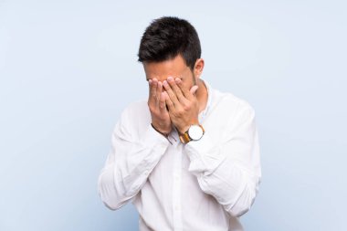 Yorgun ve hasta ifade ile izole mavi arka plan üzerinde yakışıklı genç adam