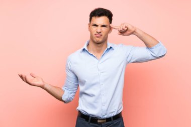 Pembe arka plan üzerinde yakışıklı adam kafasına parmak koyarak delilik jest yapma