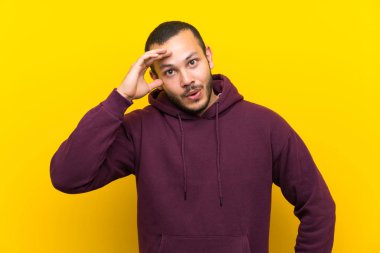 Sarı duvara Sweatshirt ile Kolombiyalı adam sadece bir şey fark etti ve çözüm niyetine sahip