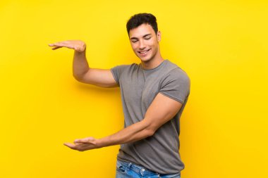 Bir reklam eklemek için copyspace tutan izole sarı duvar üzerinde Yakışıklı adam