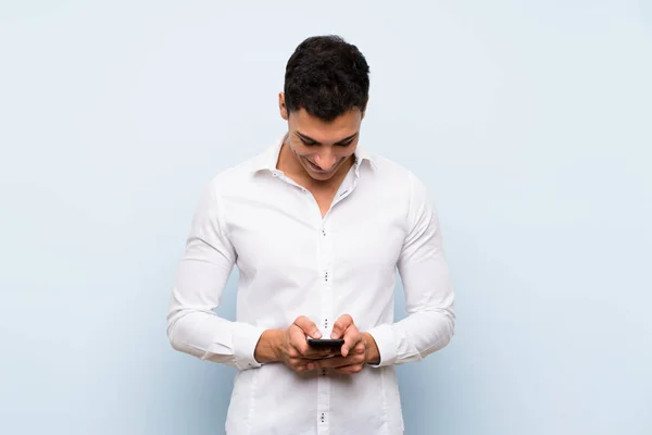 Hombre Guapo Sobre Pared Azul Enviando Mensaje Con Móvil —  Fotos de Stock