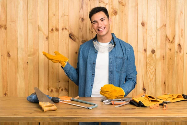 Craftsmen man over wood background holding copyspace imaginary on the palm