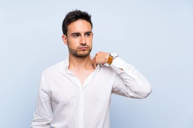 Yorgun ve hasta ifade ile izole mavi arka plan üzerinde yakışıklı genç adam