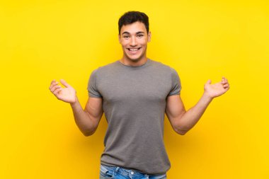 Şok yüz ifadesi ile izole sarı duvar üzerinde Yakışıklı adam