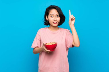 Asyalı Genç kadın, bir parmak yukarı kaldırarak çözüm anlar niyetinde tahıllar bir kase tutan