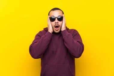 Gözlük ve sürpriz sarı duvar üzerinde Sweatshirt ile Kolombiyalı adam