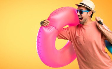 Turuncu arka planda hızlı çalışan yaz tatilinde şapka ve güneş gözlüğü olan adam