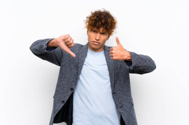 İzole beyaz duvar üzerinde moda Afrikalı Amerikan adam iyi-kötü işareti yapma. Evet ya da değil arasında kararsız