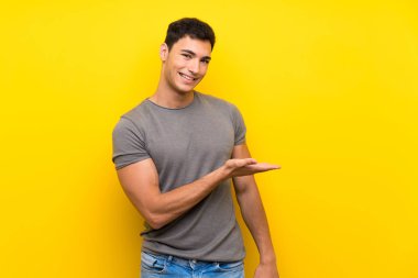 Izole sarı duvar üzerinde Yakışıklı adam doğru gülümseyerek bakarken bir fikir sunan