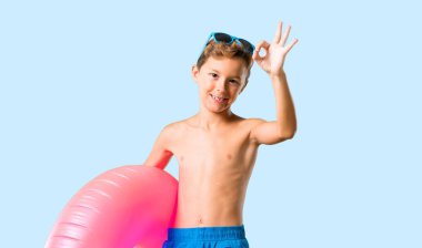 Yaz tatilinde çocuk izole mavi arka planda parmaklar ile ok işareti gösteren