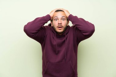 Sürpriz yüz ifadesi ile yeşil duvara Sweatshirt ile Kolombiyalı adam