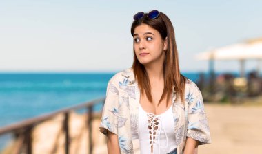 Yaz tatillerinde bikinili genç kadın plajdaki yan görünümlü şüphe jest yapma