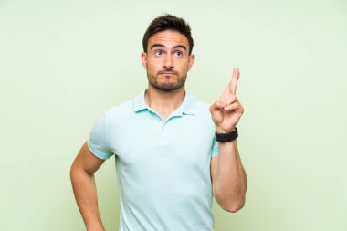 Parmaklar geçiş ve en iyi isteyen ile izole arka plan üzerinde yakışıklı genç adam