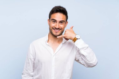 İzole mavi arka plan üzerinde yakışıklı genç adam telefon jest yapma. Bana geri çağrı işareti