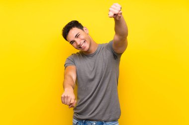 Izole sarı duvar üzerinde Yakışıklı adam gülümserken size parmak