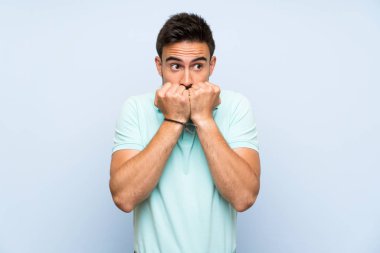 İzole arka plan üzerinde yakışıklı genç adam sinir ve ağız eller koyarak korkuyor