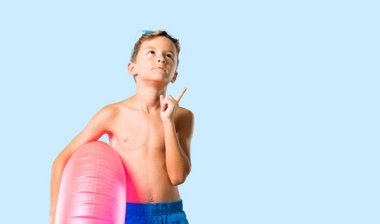 Çocuk yaz tatili ayakta ve izole mavi arka plan üzerinde bir fikir düşünme