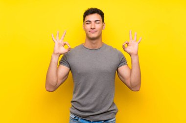 Zen poz izole sarı duvar üzerinde Yakışıklı adam