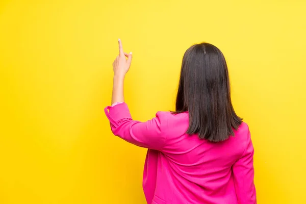 Jovem Mulher Sobre Fundo Amarelo Isolado Apontando Para Trás Com — Fotografia de Stock