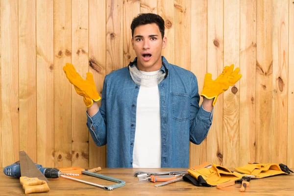 Craftsmen man over wood background with surprise facial expression
