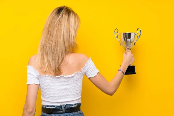 Mladé Blondýny Žena Přes Izolované Žluté Zdi Drží Trofej — Stock fotografie