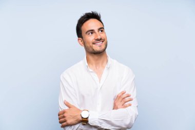 İzole mavi arka plan üzerinde yakışıklı genç adam mutlu ve gülümseyen