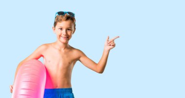 Çocuk yaz tatili tarafına parmak işaret ve izole mavi arka planda bir ürün sunma