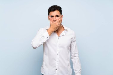 Elleriyle ağız kapsayan mavi duvar üzerinde Yakışıklı adam