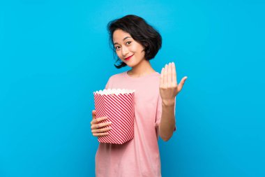 Asyalı Genç kadın el ile gelmek için davet popcorns yeme. Geldiğin için mutluyum.