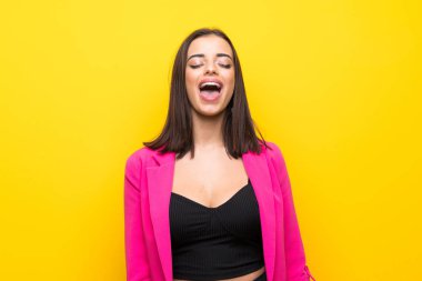 İzole edilmiş sarı arka planda genç bir kadın ağzı açık bağırıyor.