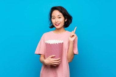 Asya genç kadın yeme popcorns işaret yukarı bir harika fikir