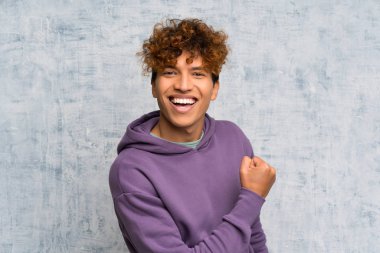 Genç Afro-Amerikan erkeği Grunge Duvarı 'nın ardında zaferi kutluyor.