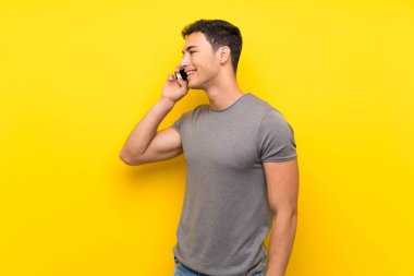 Cep telefonu ile bir konuşma tutmak izole sarı duvar üzerinde Yakışıklı adam