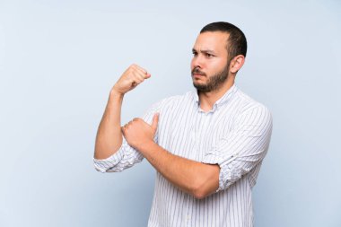 İzole mavi duvar üzerinde Kolombiyalı adam güçlü jest yapıyor