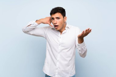 Mavi duvar üzerinde yakışıklı adam telefon jest yapma ve şüphe