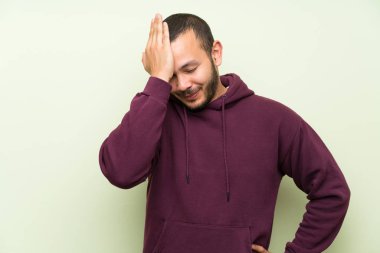 Yeşil duvara Sweatshirt ile Kolombiyalı adam yüz ifade şaşırtmak ile şüphe var