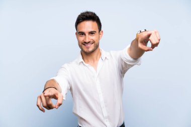 Gülümseyen sırasında izole mavi arka plan puan parmak üzerinde yakışıklı genç adam